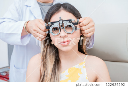Hands of optometrist examining patient with optometrist trial frame. Young patient with optometrist trial frame Hands of optometrist examining patient with optometrist trial frame. Young patient with optometrist trial frame 122926292