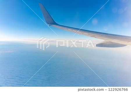 View from the airplane window at a beautiful cloudy sky and the airplane wing View from the airplane window at a beautiful cloudy sky and the airplane wing 122926766