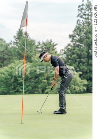 一名男高爾夫球手試圖將球放入高爾夫球場的球洞中 122926998