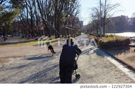 冬天的早晨,一位老年婦女帶著她的狗在公園散步 冬天的早晨,一位老年婦女帶著她的狗在公園散步 122927304