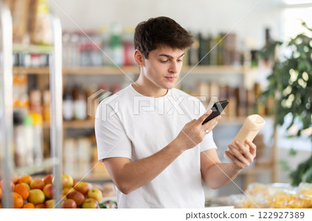 Male buyer checks suitability - scans QR code on jar of mayonnaise label in grocery store Male buyer checks suitability - scans QR code on jar of mayonnaise label in grocery store 122927389