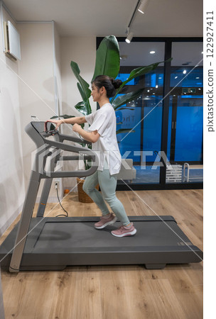 年輕女子在室內健身房的跑步機上跑步 年輕女子在室內健身房的跑步機上跑步 122927411