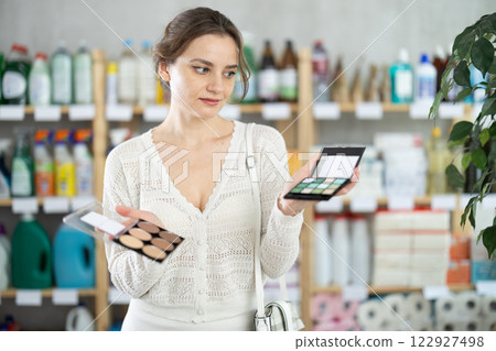 Young woman choosing eyeshadow and sculptor in store Young woman choosing eyeshadow and sculptor in store 122927498