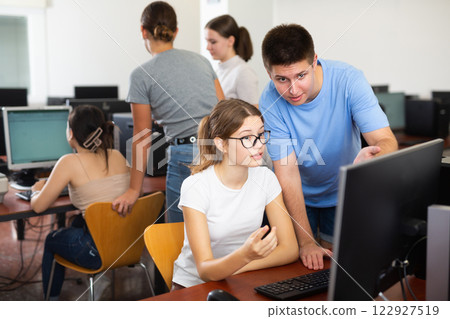 Smart male teenager giving a clue to the female co-learner while she is using pc in the computer classrooms Smart male teenager giving a clue to the female co-learner while she is using pc in the computer classrooms 122927519