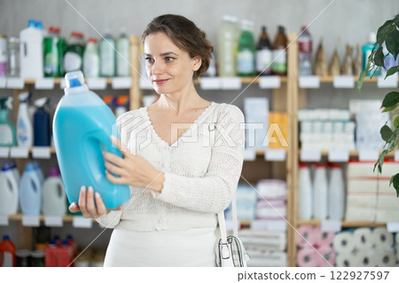 Housewife purchases household chemicals in store and chooses liquid laundry detergent 122927597