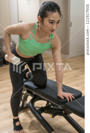 Young woman doing strength training in an indoor gym 122927608