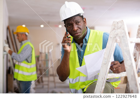 Man builder having telephone conversation in construction site Man builder having telephone conversation in construction site 122927648