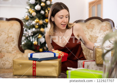 Happy young woman prepares Christmas presents Happy young woman prepares Christmas presents 122927707
