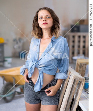Pretty woman in denim shirt posing next to a stepladder in room being renovated 122927711