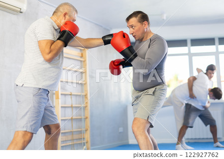Men in boxing gloves punch deliver blow each other during training sparring session. Men in boxing gloves punch deliver blow each other during training sparring session. 122927762