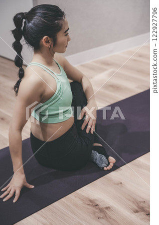 A young woman stretching in training clothes indoors A young woman stretching in training clothes indoors 122927796