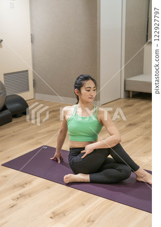 A young woman stretching in training clothes indoors A young woman stretching in training clothes indoors 122927797