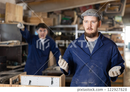 Disgruntled furniture factory owner yells at careless worker 122927828