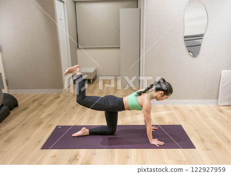 A young woman wearing training clothes doing yoga in an indoor gym 122927959