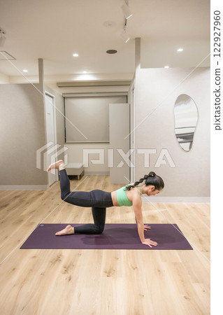 A young woman wearing training clothes doing yoga in an indoor gym A young woman wearing training clothes doing yoga in an indoor gym 122927960