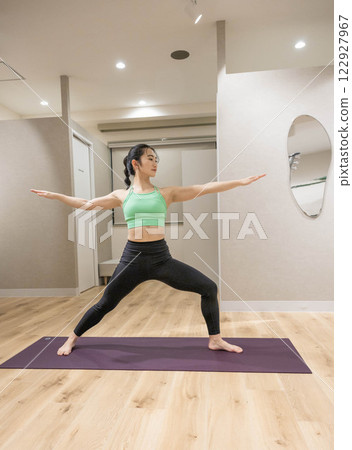 一名身穿訓練服的年輕女子在室內健身房做瑜伽 122927967