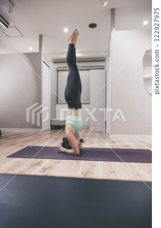 A young woman wearing training clothes doing yoga in an indoor gym 122927975