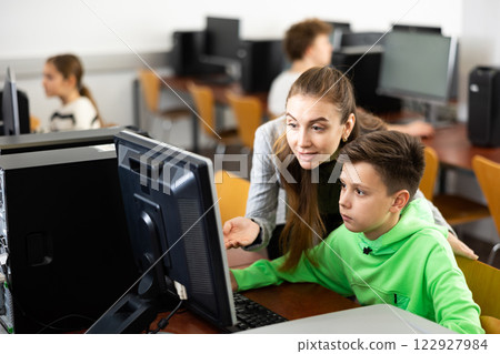 Teacher helping boy to solve computer problem 122927984