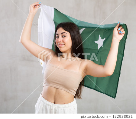 Happy young woman with flag of Pakistan against unicoloured background Happy young woman with flag of Pakistan against unicoloured background 122928021