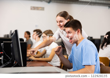 Positive young student emotionally reacting while working at pc in computer class Positive young student emotionally reacting while working at pc in computer class 122928135
