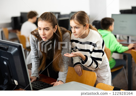 Teacher explaining task solution to pupil during computer science lesson Teacher explaining task solution to pupil during computer science lesson 122928164