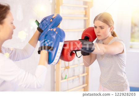 Teen girl in punch mitts boxing Teen girl in punch mitts boxing 122928203