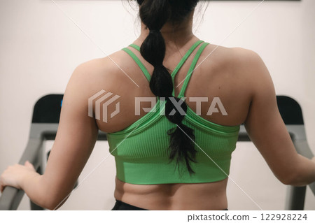 一名身穿訓練服的年輕女子在健身房的跑步機上跑步 122928224