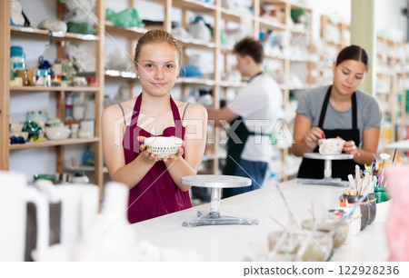 Teenage girl posing with ceramic cup in ceramic workshop 122928236