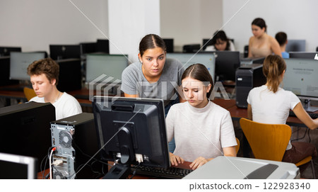 Young female teacher working with schoolgirl in computer class of library Young female teacher working with schoolgirl in computer class of library 122928340