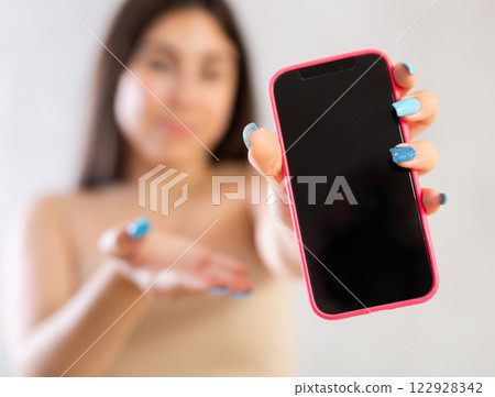 Mobile phone held in hand against blurred background 122928342