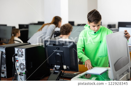 Teenage boy copies documents on scanning device 122928345