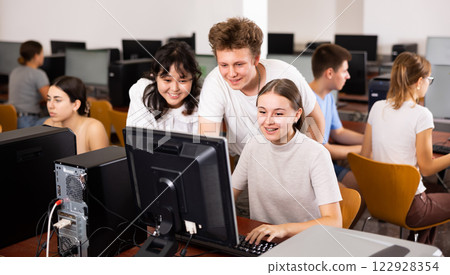 Cheerful teenager boy and girls studying in computer class Cheerful teenager boy and girls studying in computer class 122928354