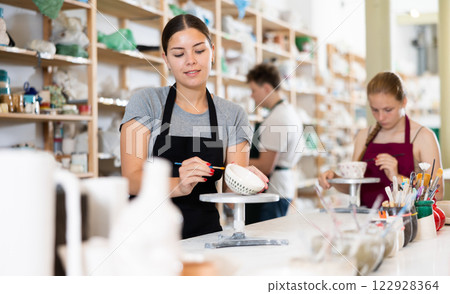 Pottery master together with his students applies a pattern to pottery in workshop Pottery master together with his students applies a pattern to pottery in workshop 122928364