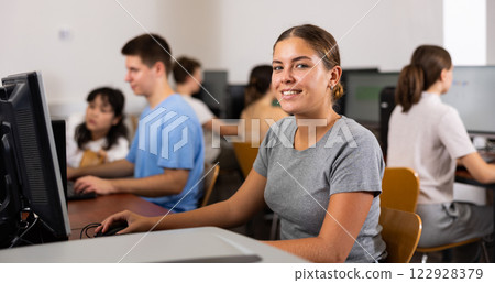 Positive female student smiling, using PC and studying computer science in the classroom Positive female student smiling, using PC and studying computer science in the classroom 122928379