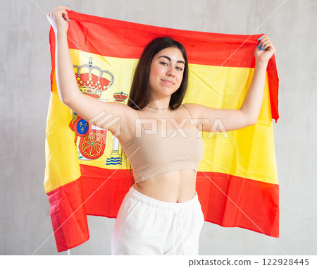 Happy young woman with flag of Spain against unicoloured background 122928445