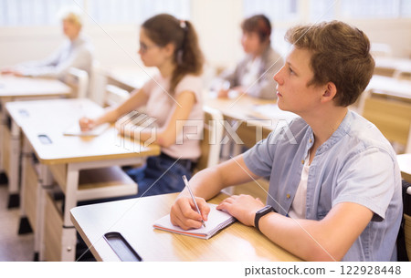 Focused teenage student writing lectures in classroom 122928448