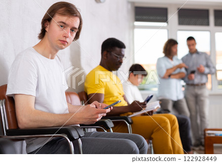 Young male visitor sitting on the bench in waiting room of clinic 122928449