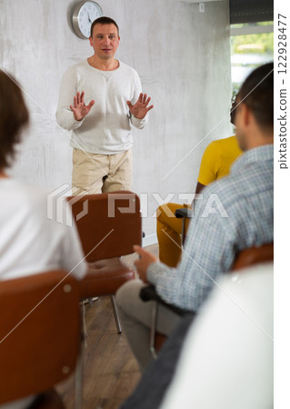 Male tutor giving lecture to group of men in study hall 122928477
