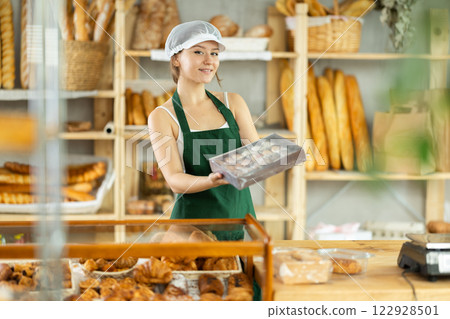 Girl entrepreneur owner of bakery holds out box with cookies in hand 122928501
