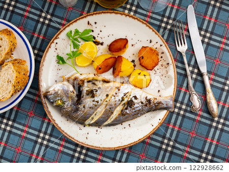 Grilled dorada with baked potatoes, lemon and parsley 122928662