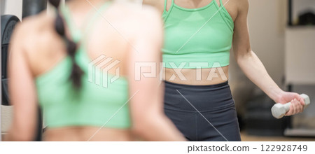 A young woman wearing training clothes doing muscle training with dumbbells A young woman wearing training clothes doing muscle training with dumbbells 122928749