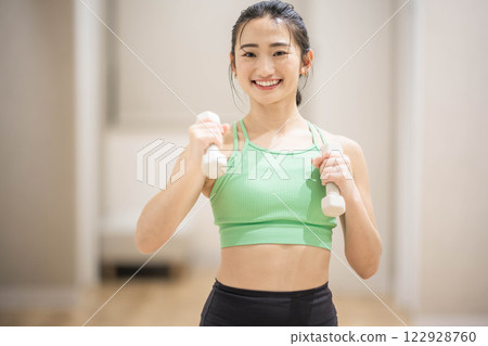 一名身穿訓練服的年輕女子用啞鈴進行肌肉訓練 一名身穿訓練服的年輕女子用啞鈴進行肌肉訓練 122928760