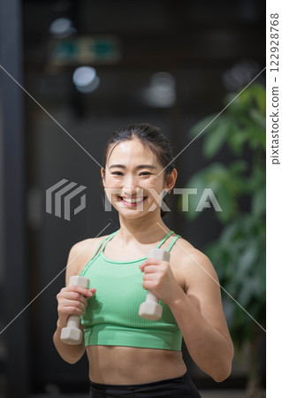 一名身穿訓練服的年輕女子用啞鈴進行肌肉訓練 122928768