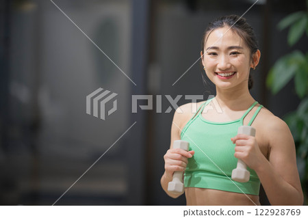 一名身穿訓練服的年輕女子用啞鈴進行肌肉訓練 122928769