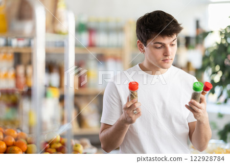 Guy examining bottles of spice bottles at grocery store Guy examining bottles of spice bottles at grocery store 122928784