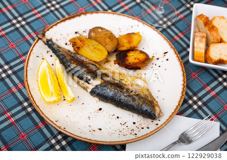 on plate, light and healthy lunch of whole fried mackerel with french fries and slice of lemon on plate, light and healthy lunch of whole fried mackerel with french fries and slice of lemon 122929038