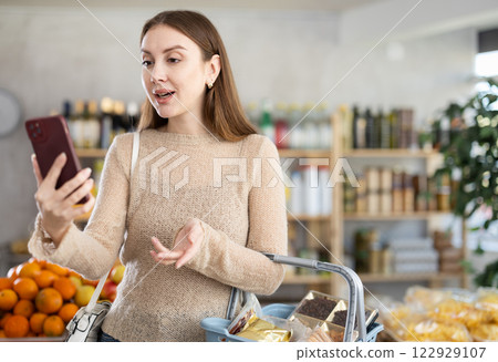 Young woman having video chat during shopping in grocery store 122929107