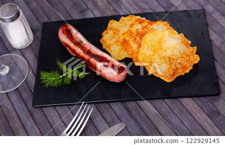 Potato pancakes with grilled sausage on wooden table 122929145