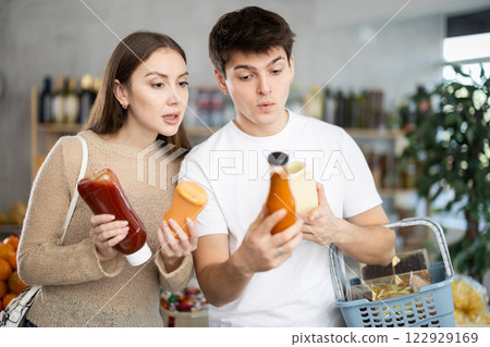 Married young happy couple chooses spicy sauce in supermarket 122929169