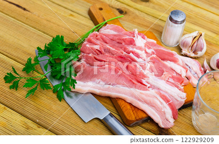 Raw pork bacon on the kitchen table along with other ingredients for making delicious lunch or dinner 122929209